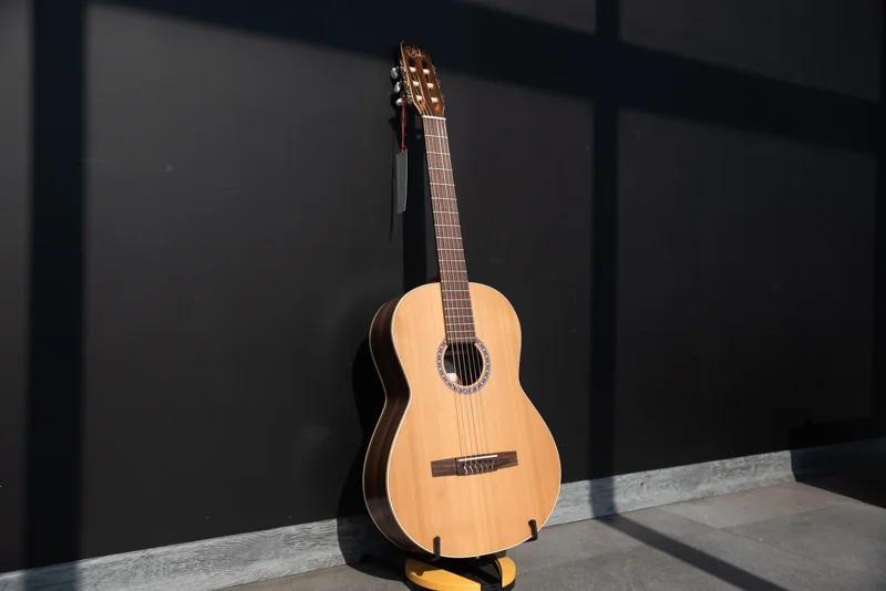 یک گیتار کلاسیک گودین مدل Presentation که به دیوار سیاه تکیه داده شده است.